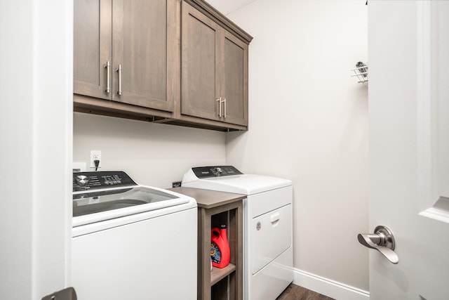 clothes washing area featuring baseboards, wood finished floors, cabinet space, and washing machine and clothes dryer