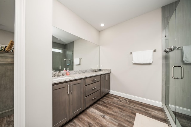 bathroom with a sink, baseboards, wood finished floors, and visible vents