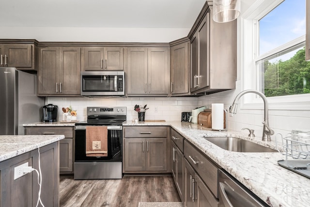 kitchen featuring backsplash, dark wood-style flooring, dark brown cabinets, a sink, and stainless steel appliances