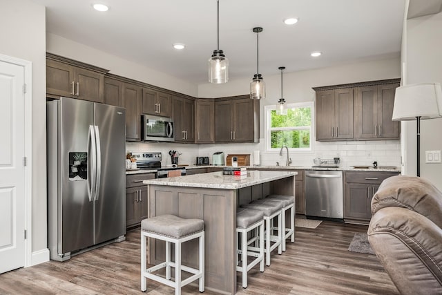 kitchen with dark wood finished floors, appliances with stainless steel finishes, dark brown cabinetry, and a kitchen breakfast bar