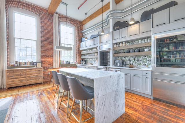 kitchen featuring a sink, a center island, a high ceiling, and brick wall