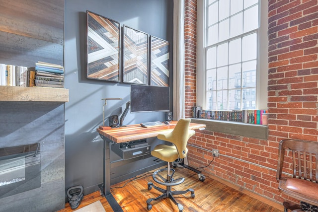 office area with hardwood / wood-style flooring and brick wall