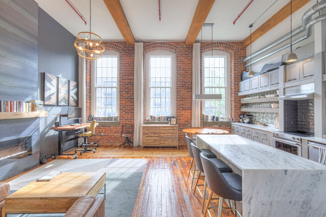 office area with brick wall, beamed ceiling, light wood-style flooring, and a wealth of natural light