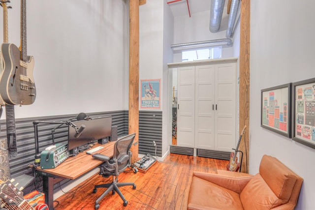 office area with wood-type flooring and a wainscoted wall