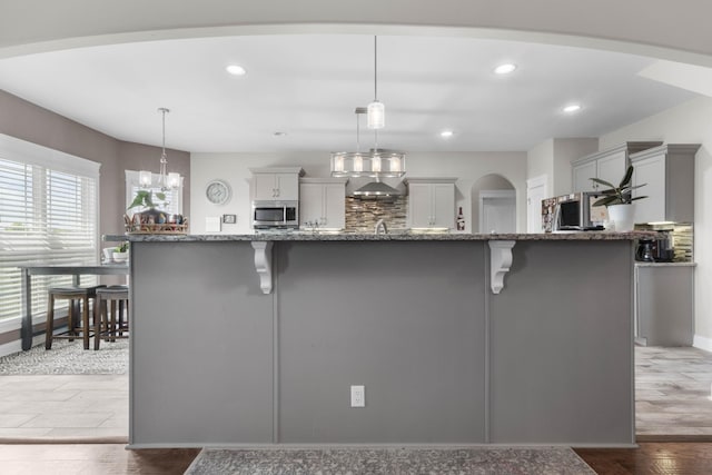 1132 Upland Ter, Clarksville, TN 37043 - kitchen featuring recessed lighting, stone counters, stainless steel microwave, and a kitchen bar