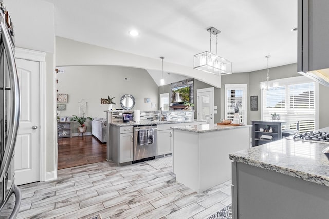 1132 Upland Ter, Clarksville, TN 37043 - kitchen featuring light stone countertops, appliances with stainless steel finishes, arched walkways, light wood-type flooring, and a kitchen island