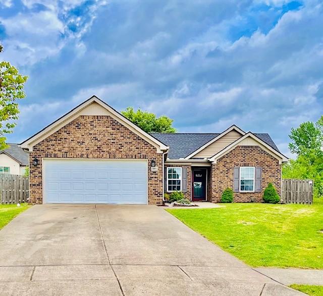 single story home with concrete driveway, brick siding, fence, and a front yard