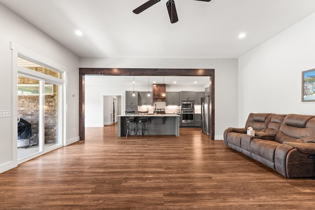 living room featuring recessed lighting, baseboards, ceiling fan, and dark wood-style floors