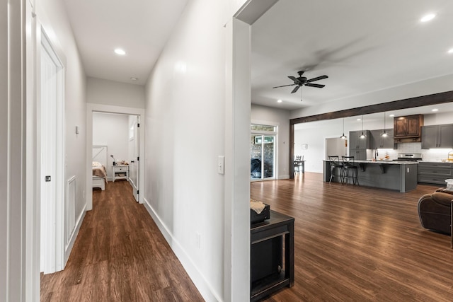 corridor with baseboards, recessed lighting, dark wood-style flooring, and a sink
