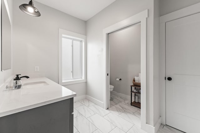 bathroom featuring vanity, baseboards, toilet, and marble finish floor