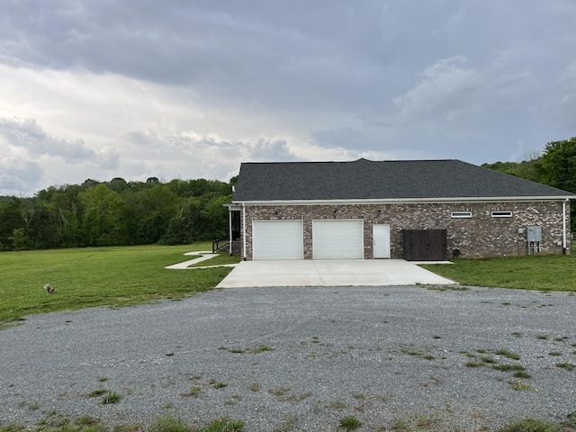 view of property exterior featuring a lawn, roof with shingles, brick siding, an attached garage, and driveway
