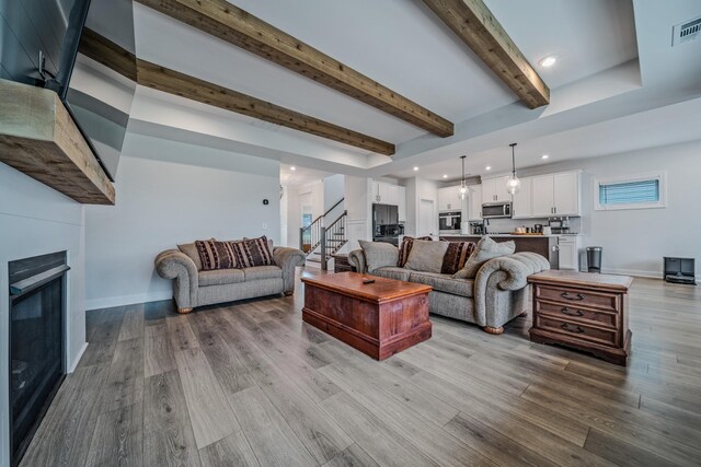 1055 Inez Dr, Smyrna, TN 37167 - living area with stairway, beam ceiling, wood finished floors, a glass covered fireplace, and recessed lighting