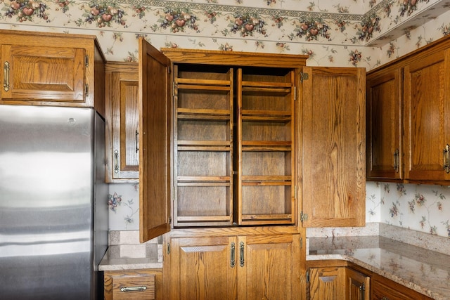 1314 Huntington Dr, Columbia, TN 38401 - kitchen with light stone counters, freestanding refrigerator, wallpapered walls, and brown cabinetry