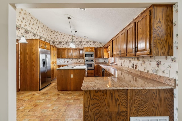 1314 Huntington Dr, Columbia, TN 38401 - kitchen featuring brown cabinetry, wallpapered walls, a sink, appliances with stainless steel finishes, and vaulted ceiling