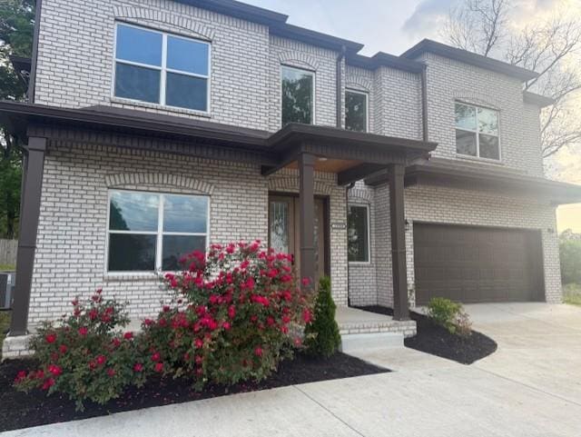 traditional-style home with a garage, central AC unit, driveway, and brick siding