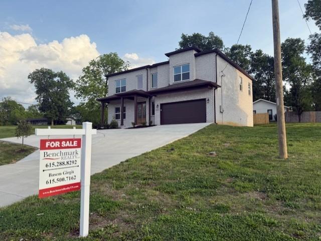 view of front of property with concrete driveway, an attached garage, fence, and a front yard