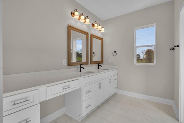 bathroom with a sink, baseboards, double vanity, and marble finish floor