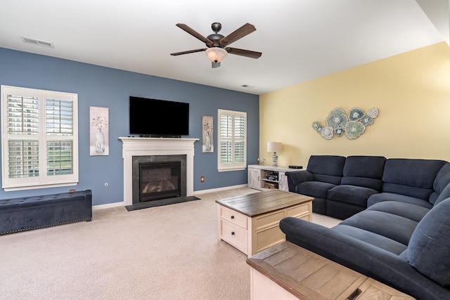 living room featuring ceiling fan, light carpet, baseboards, a fireplace with flush hearth, and visible vents