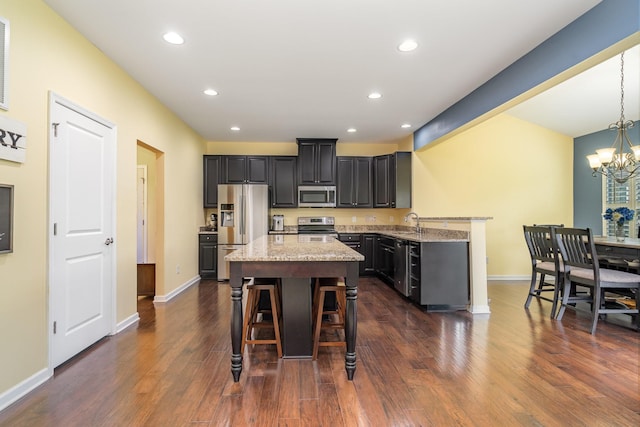 kitchen featuring stainless steel appliances, recessed lighting, a kitchen bar, a kitchen island, and dark wood-style floors