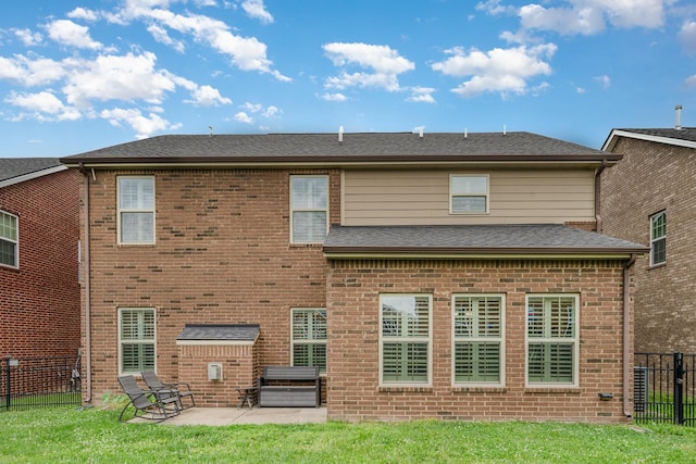 rear view of property with brick siding, a patio area, fence, and a lawn