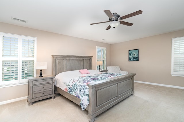 bedroom with light colored carpet, baseboards, ceiling fan, and visible vents