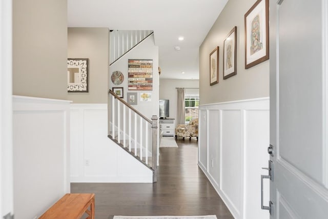 entrance foyer featuring wainscoting, a decorative wall, stairs, and dark wood-type flooring