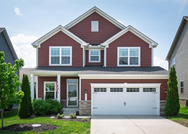 craftsman-style house featuring an attached garage, driveway, and stone siding