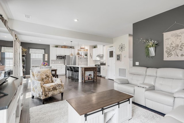 living area featuring visible vents, recessed lighting, and dark wood-style flooring