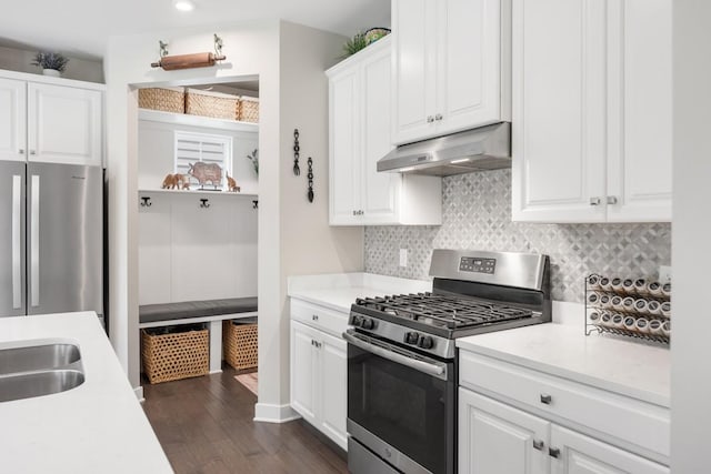 kitchen featuring light countertops, dark wood finished floors, stainless steel appliances, tasteful backsplash, and under cabinet range hood