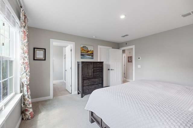 bedroom with visible vents, light carpet, and multiple windows