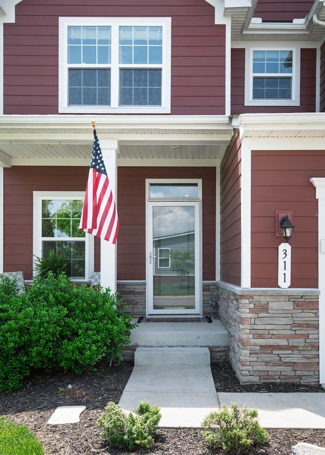 entrance to property with covered porch and stone siding