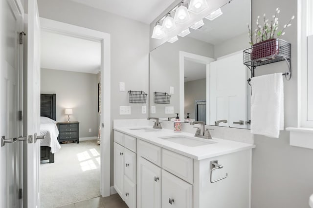 ensuite bathroom with connected bathroom, double vanity, baseboards, and a sink