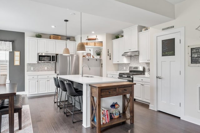 kitchen with a sink, decorative backsplash, stainless steel appliances, and under cabinet range hood