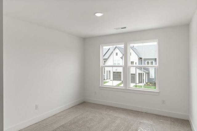 spare room with baseboards, visible vents, and light carpet