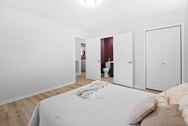 bedroom with ensuite bath, baseboards, wood finished floors, ornamental molding, and a closet