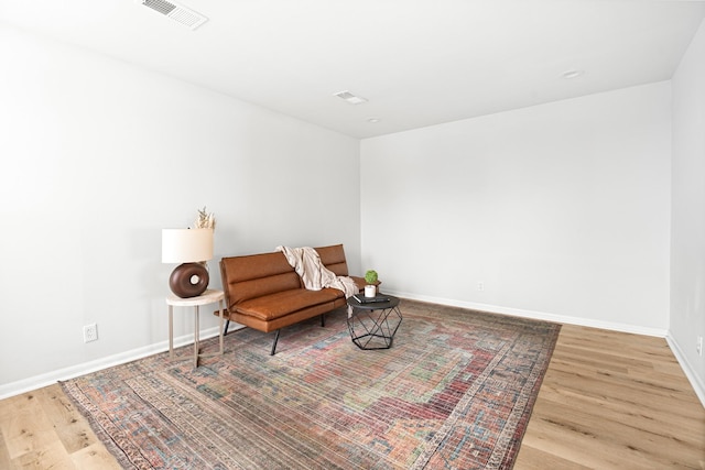 sitting room featuring baseboards, visible vents, and wood finished floors