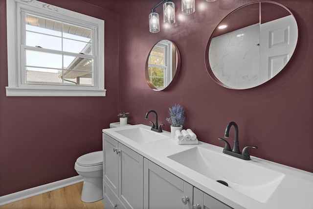 bathroom with a sink, baseboards, toilet, and wood finished floors