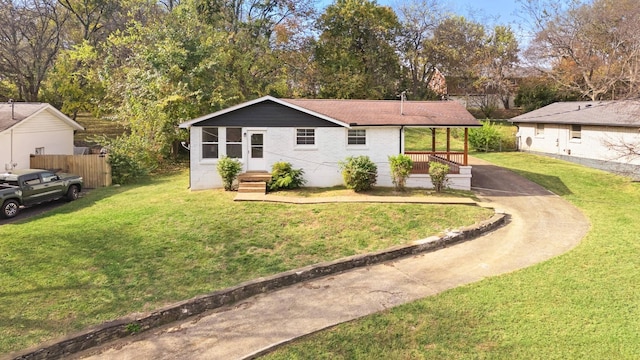 ranch-style home featuring a front lawn, fence, brick siding, a porch, and driveway