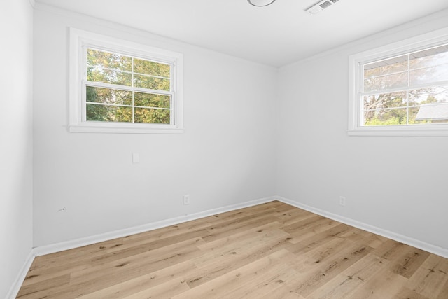 empty room with baseboards, visible vents, and light wood finished floors