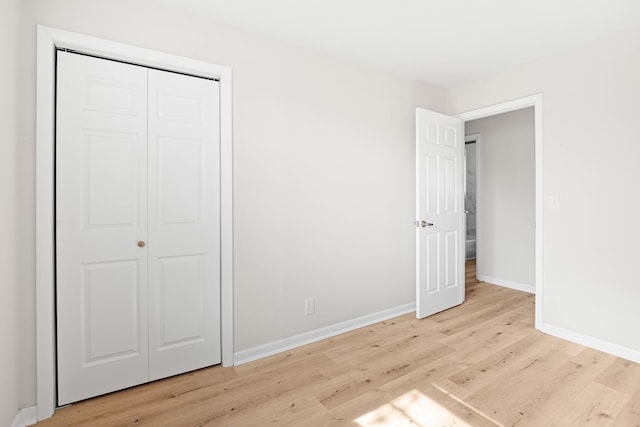 unfurnished bedroom featuring baseboards, a closet, and light wood-type flooring