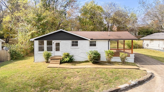 ranch-style house with fence, a shingled roof, brick siding, and a front yard