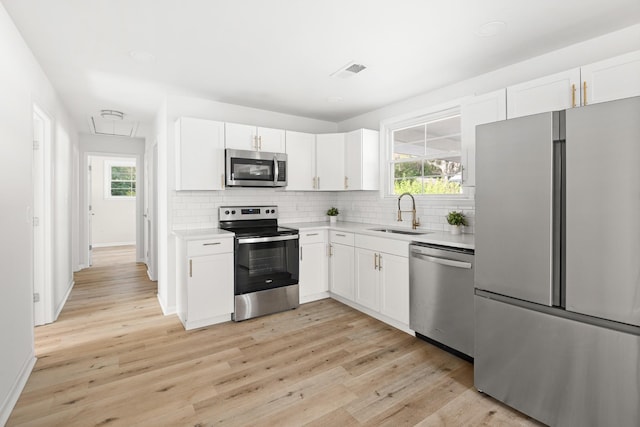 kitchen with visible vents, decorative backsplash, light countertops, a sink, and stainless steel appliances