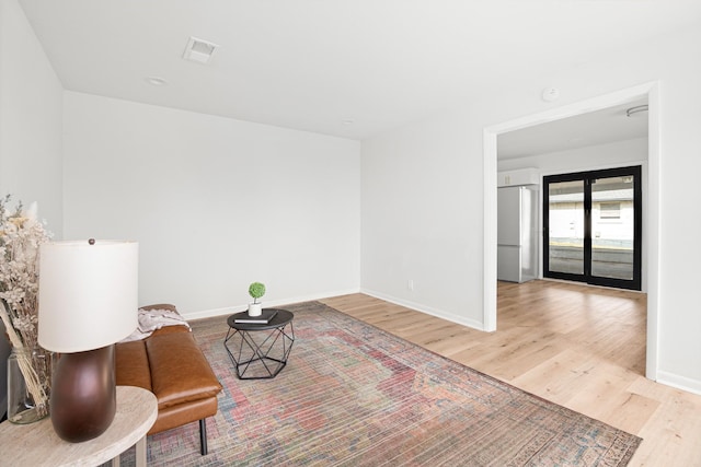 living area featuring baseboards, wood finished floors, and visible vents