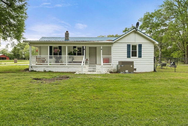 rear view of house featuring a porch, a lawn, a chimney, and central air condition unit