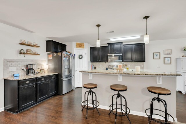 kitchen with dark cabinetry, stainless steel appliances, visible vents, and decorative backsplash