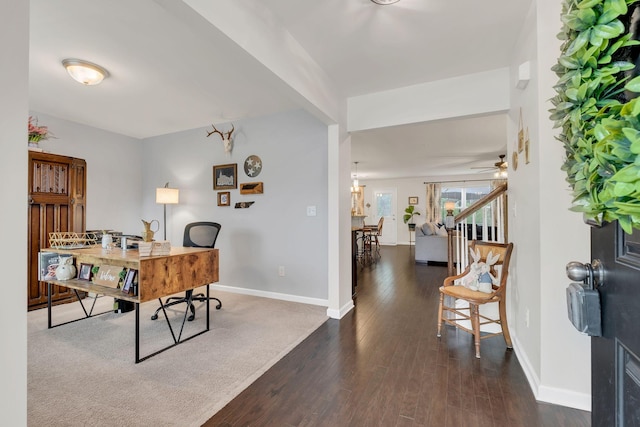 office area with dark wood-type flooring, a ceiling fan, and baseboards