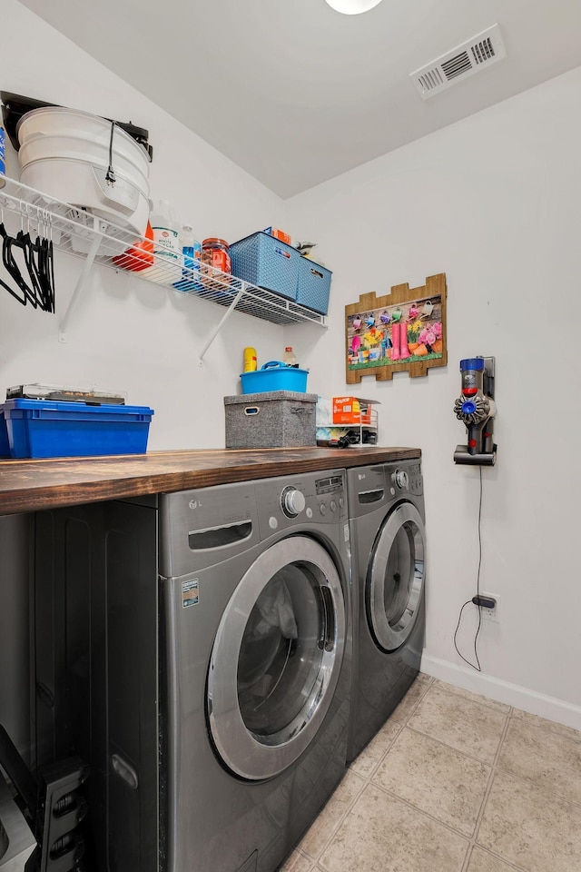 laundry room with washer and dryer, laundry area, baseboards, light tile patterned floors, and visible vents