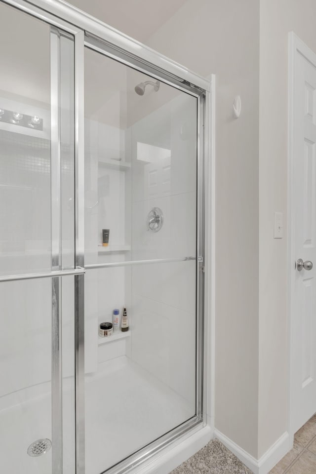 full bathroom featuring baseboards and a shower stall