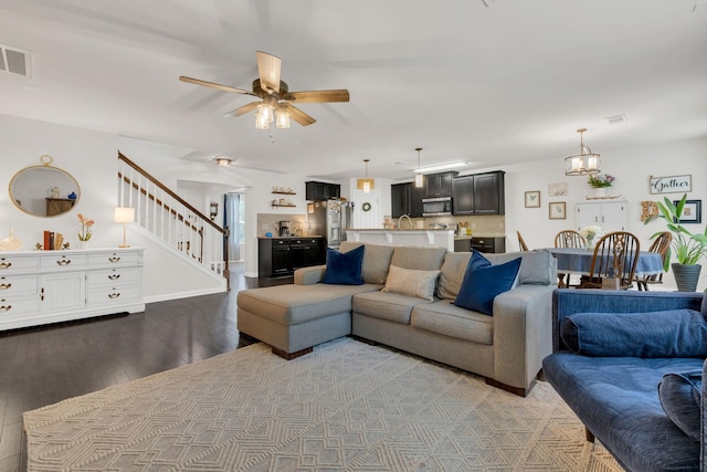 living area featuring stairway, ceiling fan, wood finished floors, and visible vents