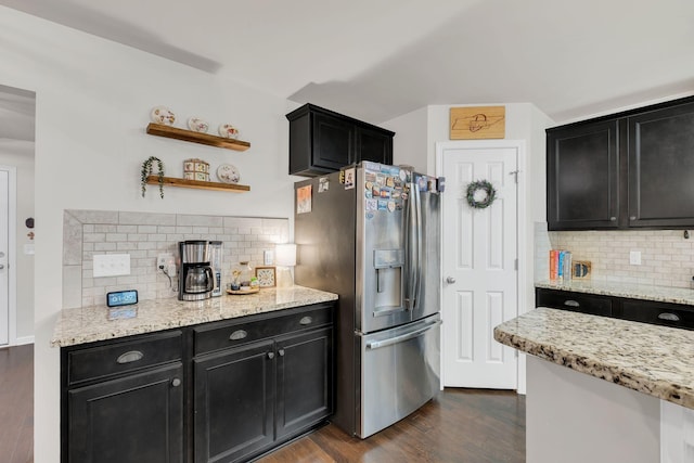 kitchen with dark wood-style flooring, dark cabinets, stainless steel fridge, and tasteful backsplash